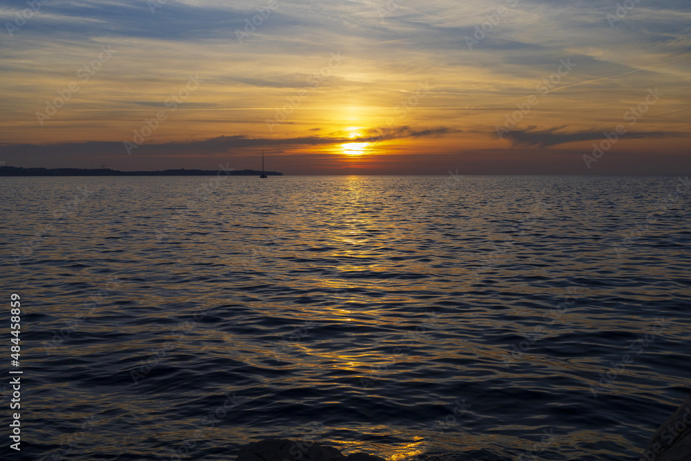 Sunset on Adriatic sea with small sailboat on horizon