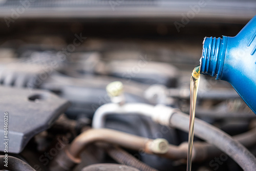 Pouring synthetic lube oil from the canister for car engine oil replacement, machine service and maintenance working photo. Close-up and selective focus.
