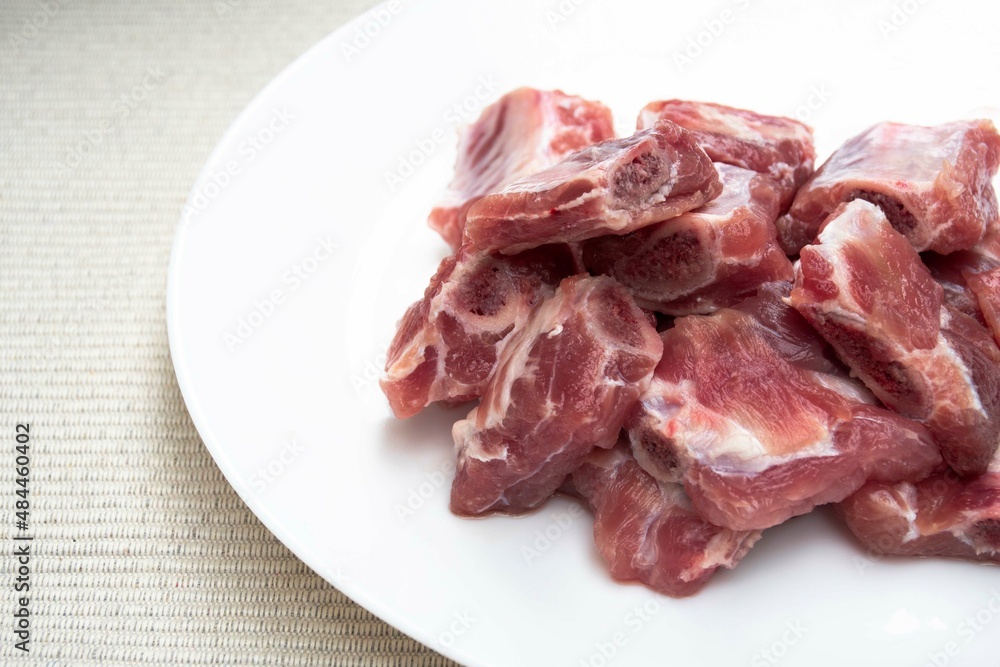 Raw minced pork ribs stack on a white plate. Raw minced pork ribs stack on a white plate.