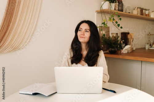 A business woman freelancer in casual clothes works online remotely using a laptop, mobile phone and technology while sitting in an indoor home office. Online education. Selective focus