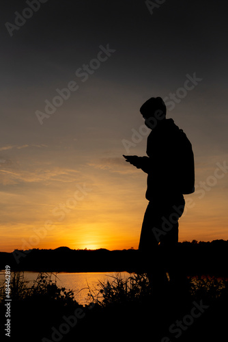 Silhouettes man standing playing with mobile phones at sunset