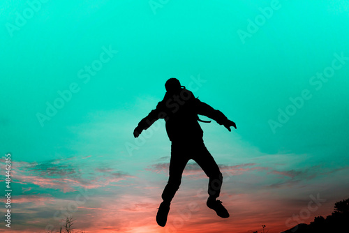 Silhouette man jump of sunset sky. Color scheme is like another world of mystery, like a person being sucked into the sky.