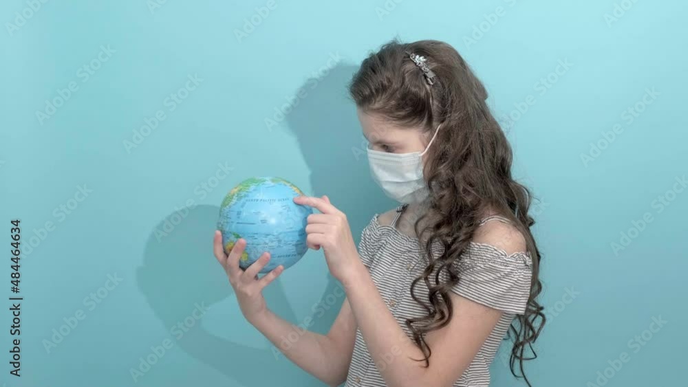 4k. Little girl holding terrestrial globe pointing at destination looking camera smiling happy. Portrait of Young girl choosing place, country for vacation isolated on blue background. Copy space 4k. Little girl holding terrestrial globe pointing at destination looking camera smiling happy. Portrait of Young girl choosing place, country for vacation isolated on blue background. Copy space