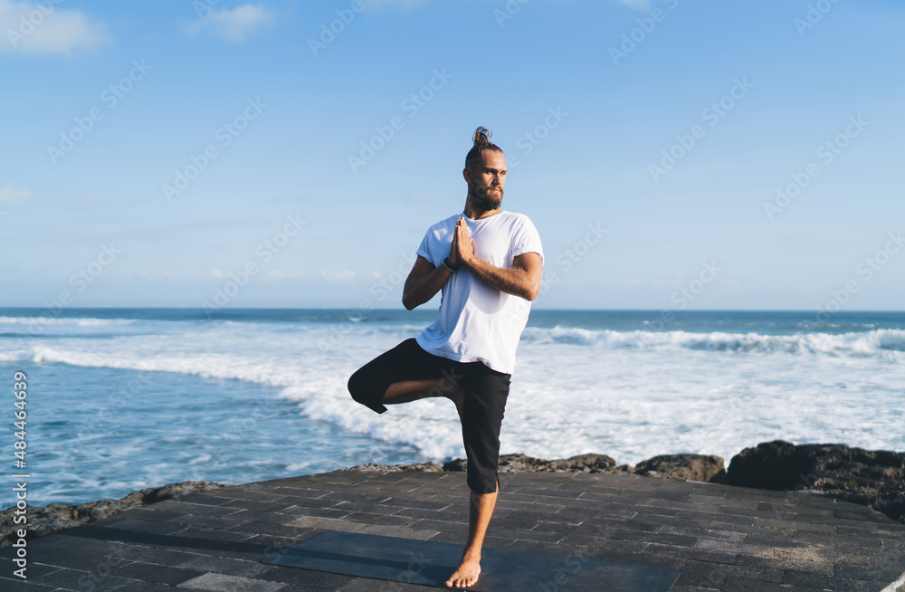 Caucasian man in sportswear reaching vitality wellness and healthy lifestyle for holistic retreat and appeasement healing with hatha yoga, young male stretching body and exercising during warm up
