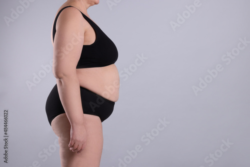Overweight woman in underwear on grey background, closeup. Space for text photo