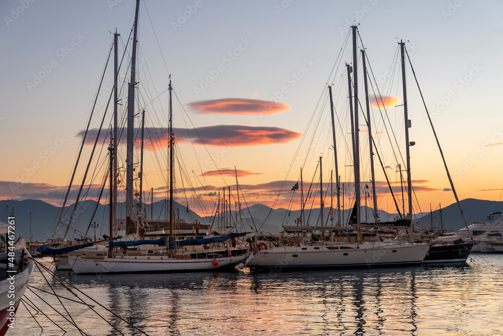 Sailboats, fishing boats and yachts reflect off the sea at sunset in the small fishing village of Aegina, on the island of Aegina, Greece.	