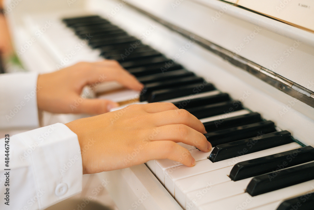 Fototapeta premium Extreme close-up hands of unrecognizable female musician performer playing on classical piano at home enjoying gentle music in free time. Lady pianist practicing piano lesson in light classroom.