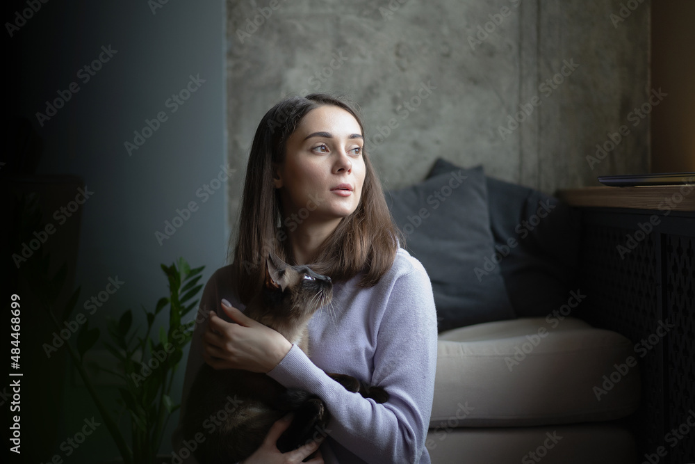 A girl with cat sits by the window A girl with cat sits by the window