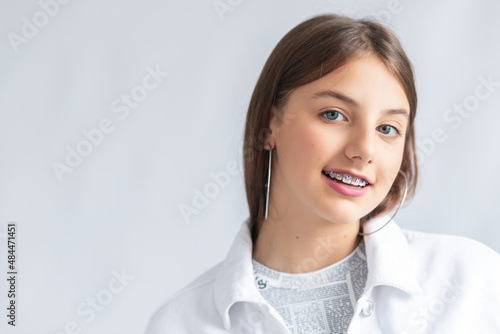 Cheerful beautiful young woman with dark hair and braces on teeth laughing isolated on a gray background