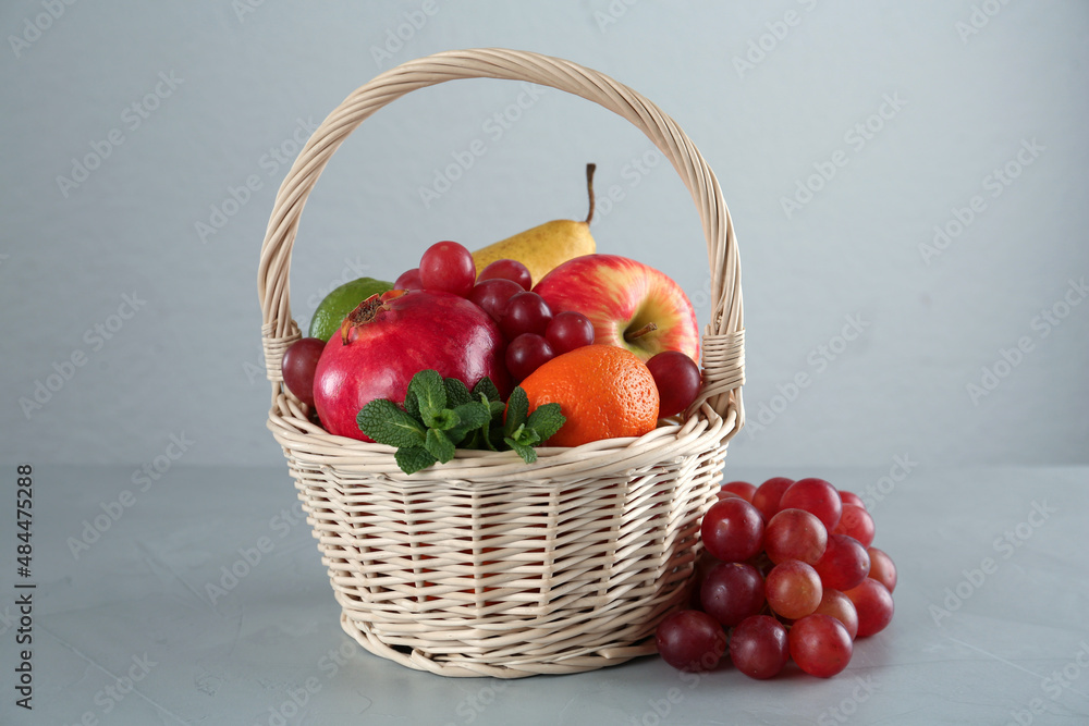 Wicker basket with different ripe fruits on grey table Wicker basket with different ripe fruits on grey table