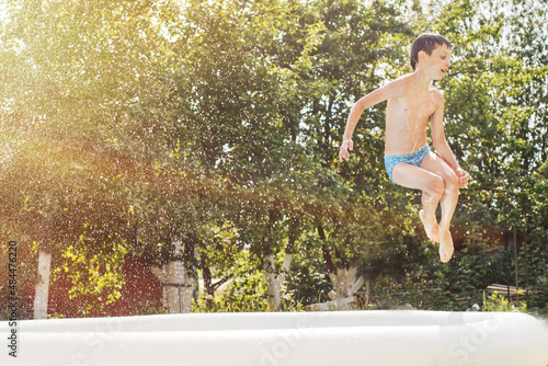 boy jumping into the swimming pool in the garden at summer