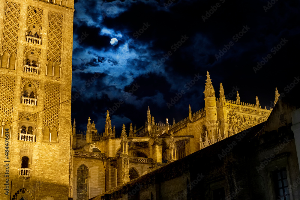 The exterior of the Cathedral of Seville, or Cathedral of Saint Mary of the See, in Seville Spain at night, one of the largest gothic cathedrals in Europe with the Giralda Tower in view.	