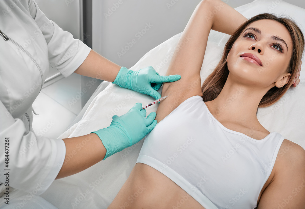 Underarm hyperhidrosis treatment. Armpit injections to prevent excessive sweating for female patient with beautician at cosmetology Underarm hyperhidrosis treatment. Armpit injections to prevent excessive sweating for female patient with beautician at cosmetology