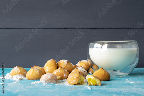 Shortbread cookies consisting of butter, flour, and jam filling, view of baked sweet cookies and a glass of milk on a wooden background, selective focus
