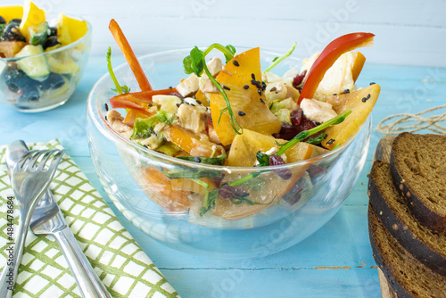 Salad with chicken and cheese, with herbs, persimmons, bell peppers. The concept of diet food. Delicious salad in a bowl on a wooden background, selective focus.
