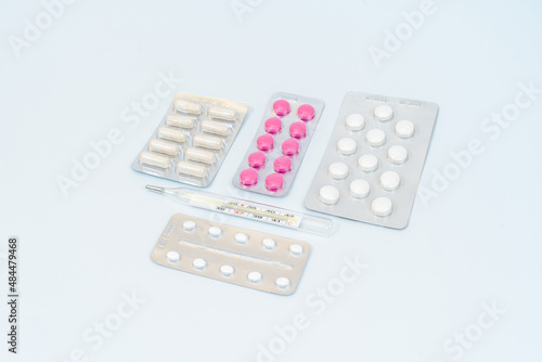 Capsules pills with thermometer and tablets in blister packaging. Isolated