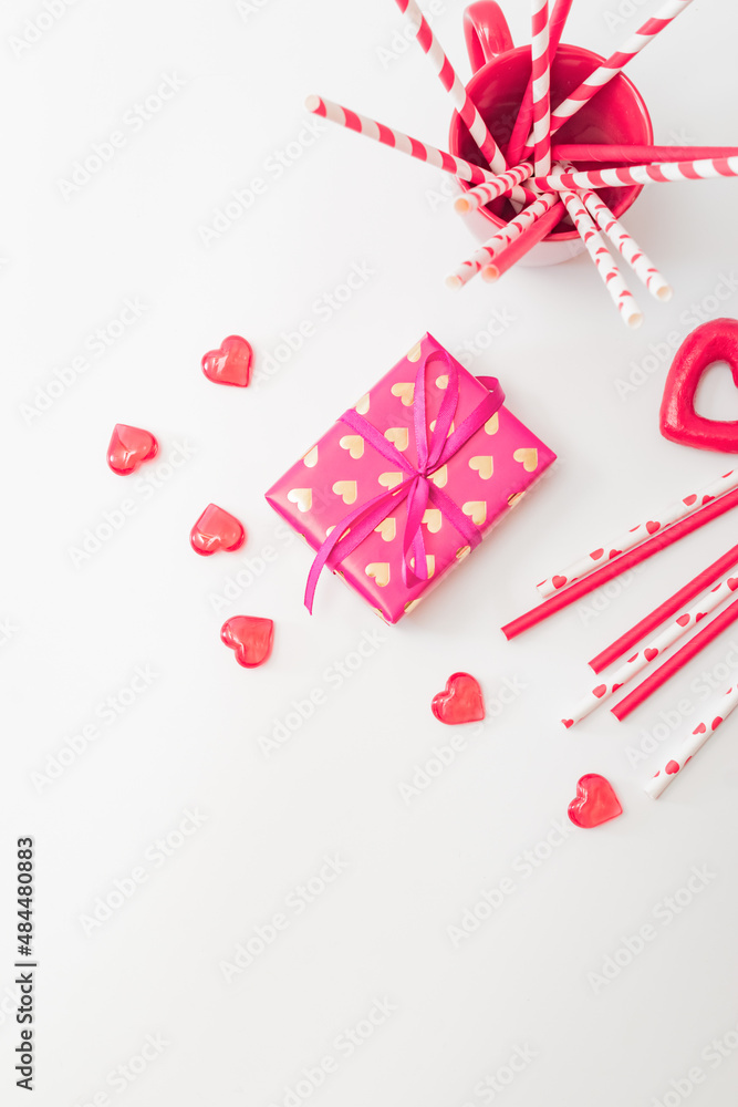 Flat lay valentines day with paper drinking straws, gift box and red hearts on a white background