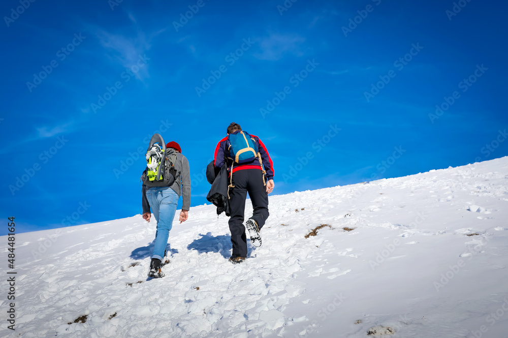Mountain hikers climb to the snowy peak