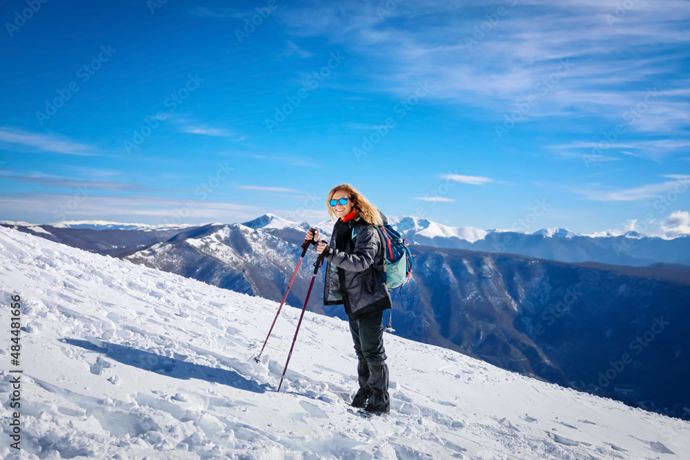 Girl on hike goes up the top of the snowy mountain.