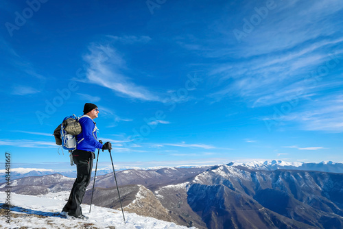 Hiker on the top of the mountain, backpack, hat and poles.