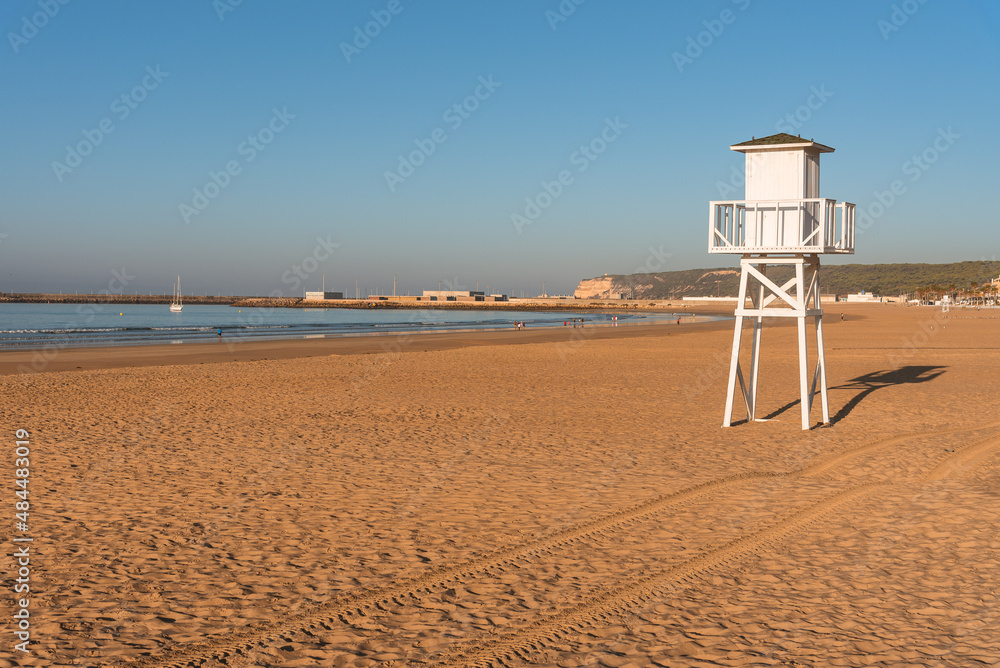 Baywatch tower in Carmen beach with the harbor of Barbate in the background, Cadiz, Andalusia, Spain Baywatch tower in Carmen beach with the harbor of Barbate in the background, Cadiz, Andalusia, Spain