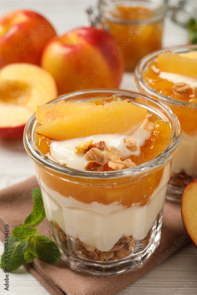 Tasty peach yogurt with granola, pieces of fruit and jam on table Tasty peach yogurt with granola, pieces of fruit and jam on table