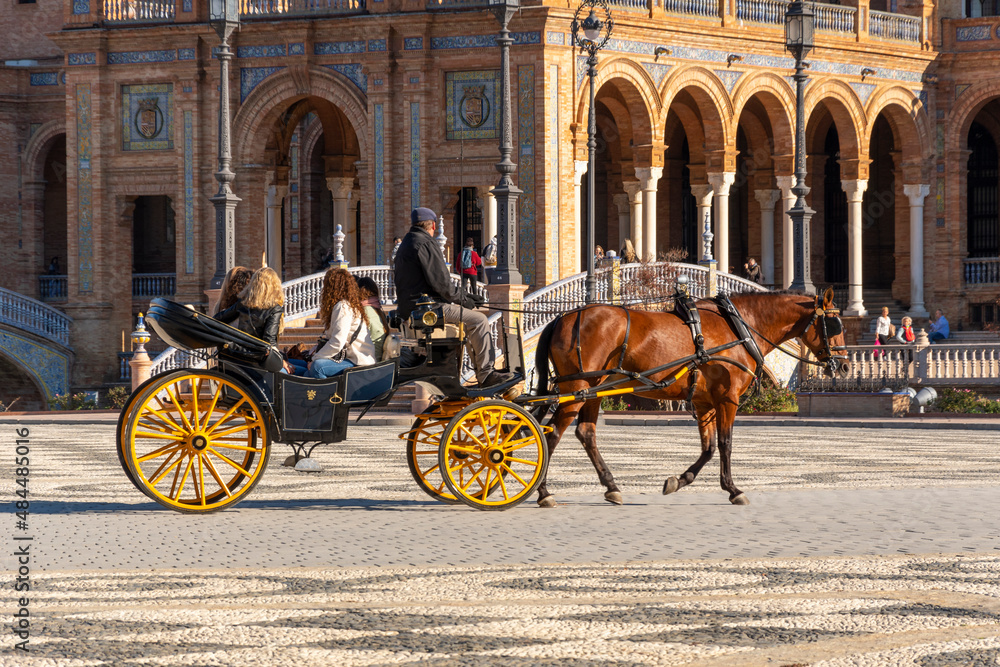 A group of female tourists enjoy a horse carriage ride through the Plaza de Espana, or Spanish Square on a summer day in the Andalusian city of Seville, Spain