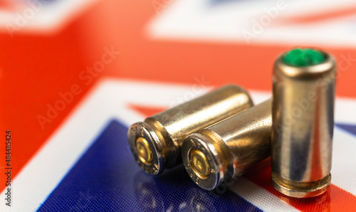 Gun bullets over the United Kingdom flag. Criminal, crime and corruption concept. UK outlaw, social problem and armed attack background photo