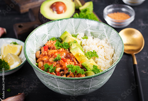 Chili con carne and couscous in bowl on dark background. Mexican cuisine.