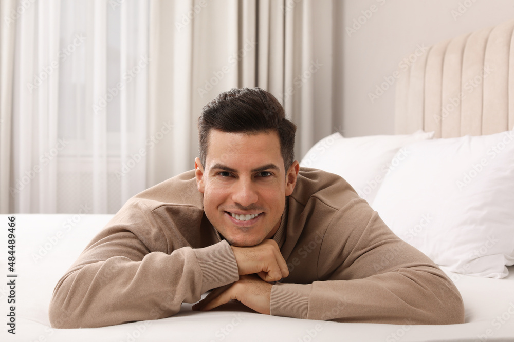 Happy man lying on bed at home