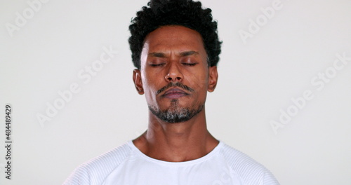 African man closing eyes trying to relax and contemplate life in meditation mindful