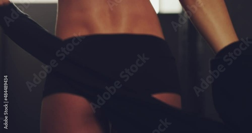 Getting out of her gym clothes. Sexy woman removing her jacket to get naked in a gym. Closeup of a slim caucasian woman undressing for exercise and a workout. Wearing shorts with her toned bum exposed