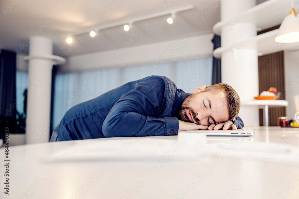 A tired businessman sleeping on his laptop at home. A tired businessman sleeping on his laptop at home.