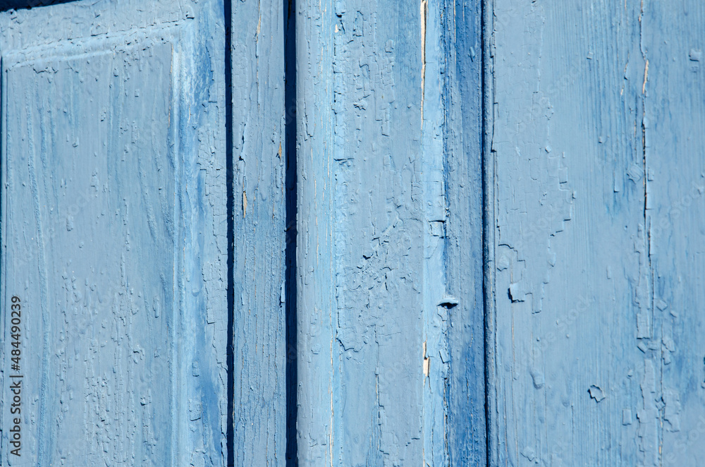Selective focus old blue cracked paint. The texture of the old emerald paint with cracks. Dried in the sun and cracked color on the wooden shutters of country house. Peeling coating. Selective focus old blue cracked paint. The texture of the old emerald paint with cracks. Dried in the sun and cracked color on the wooden shutters of country house. Peeling coating.