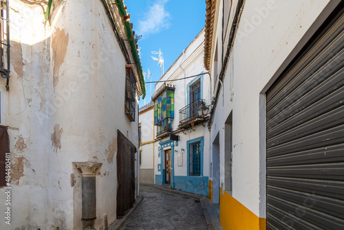 A narrow alley or road through the Jewish quarter with white walls and colorful accents in the historic old town village center of Cordoba, Spain. © Kirk Fisher