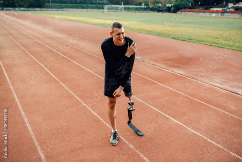 A sportsman with artificial leg have painful shoulder injury while standing at stadium,