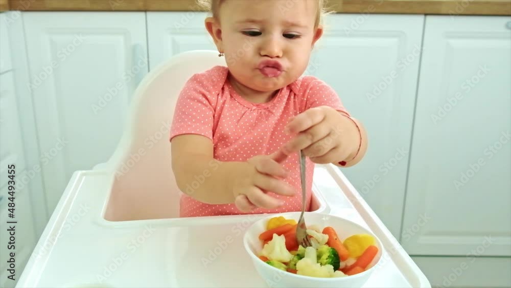 Baby eats vegetables on a chair. Selective focus. Baby eats vegetables on a chair. Selective focus.