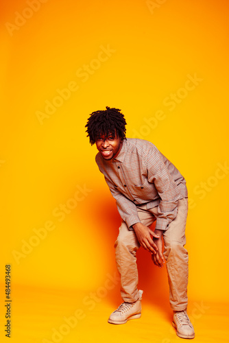 young handsome african american guy student posing cheerful and gesturing on yellow background, lifestyle people concept