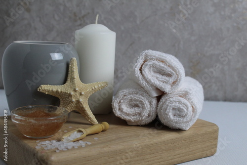 spa massage home care relax. Towels white candles scrub clay salt lie on a tray on a gray background with space for text