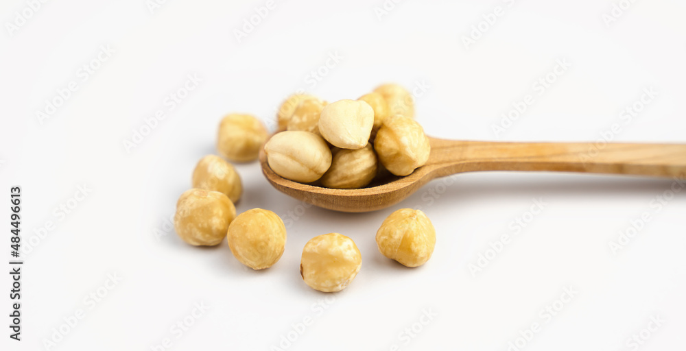 Hazelnut in wooden spoon isolated on white background. Close-up. Banner. Selective focus. Hazelnut in wooden spoon isolated on white background. Close-up. Banner. Selective focus.