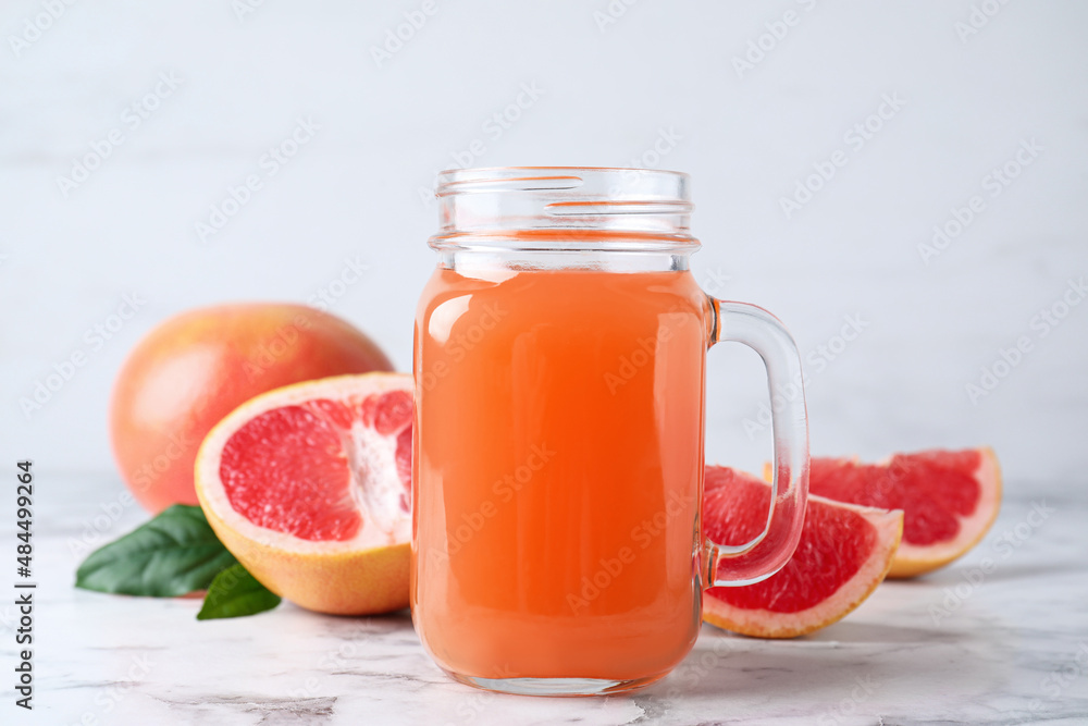 Tasty freshly made grapefruit juice on white marble table Tasty freshly made grapefruit juice on white marble table