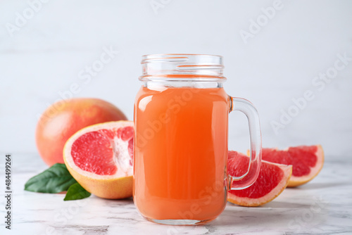 Tasty freshly made grapefruit juice on white marble table