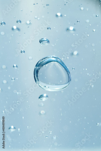 Bubbles of air or oxygen in water or gel. Can also represent a molecule or oil particle in a transparent liquid. Round and blue floating bubbles similar to hyaluronic acid. Shallow depth of field.