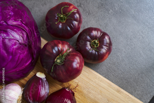 Fresh fruits and vegetables. Organic, red onions, red cabbage, purple tomatoes. Dark heirloom tomatoes. Farmer's market winter harvest. Purple vegetables.