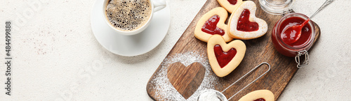 Board with tasty heart-shaped cookies and jam with cup of coffee on light background with space for text. Valentine's Day celebration photo