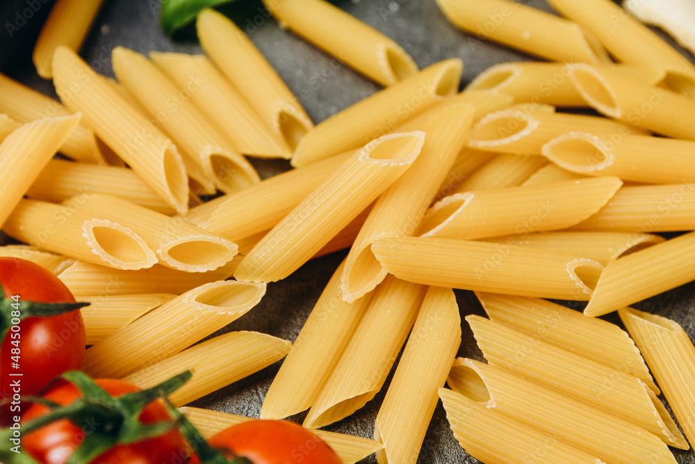 Pasta spaghetti or penne, parmesan cheese, olive oil, spices, basil, tomato sauce and fresh tomatoes. top view. Italian food background. Pasta spaghetti or penne, parmesan cheese, olive oil, spices, basil, tomato sauce and fresh tomatoes. top view. Italian food background.