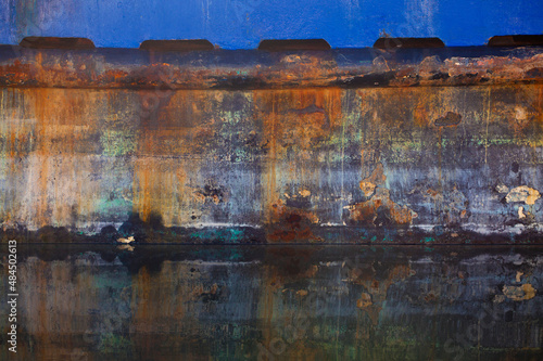 Vibrant colors and patterns on rust from an old fishing boat and its reflections 
