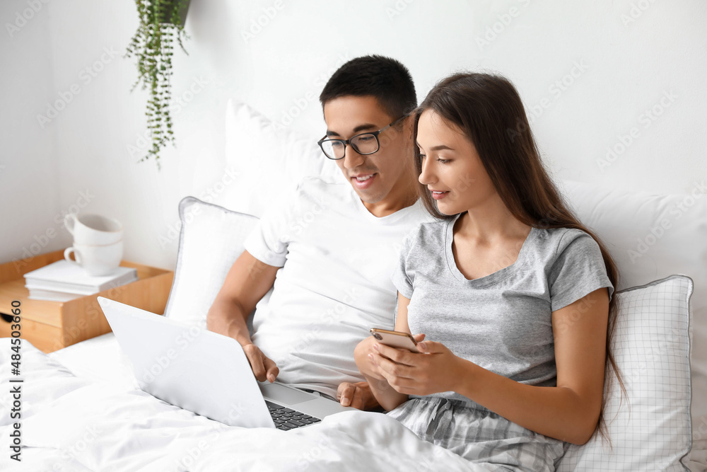 Young couple using laptop in bed Young couple using laptop in bed