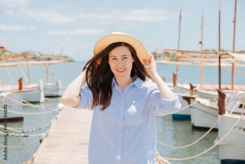 person on the yacht. Woman in straw hat smiles and is in a good mood. Holiday or vacation in Spain or Greece. Boater goes on vacation. Woman at the jetty 