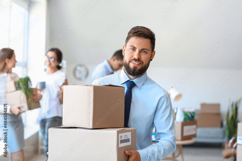 Handsome man holding boxes with things in office on moving day Handsome man holding boxes with things in office on moving day